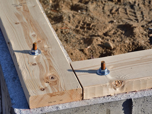 Foundation sill plate and anchor-bolt connection visible during residential construction.