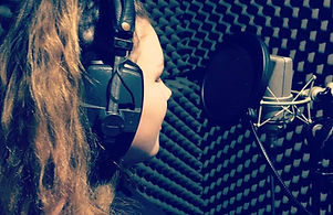 Young girl singing into microphone in recording studio