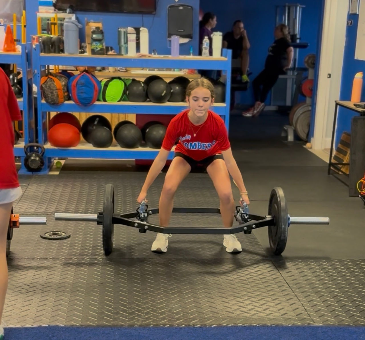 Softball player doing a deadlift with a trap bar.