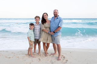 Ryan and Angie Payne at the beach with their kids posing for a family photo
