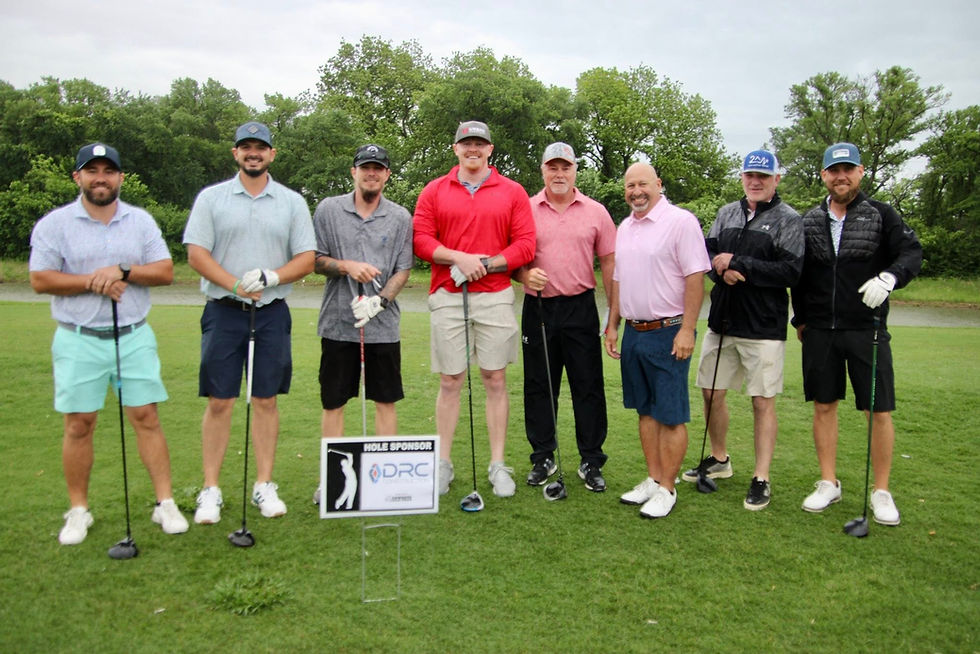 Group of golfers posing before teeing off posing in front of a sponsor sign.