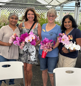 Four ladies posing with orchids in hand in a green house