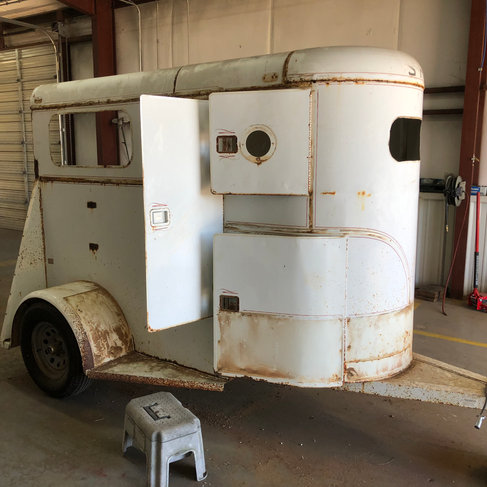 Side view of a classic one horse trailer that has rusted out and is in need of restoration