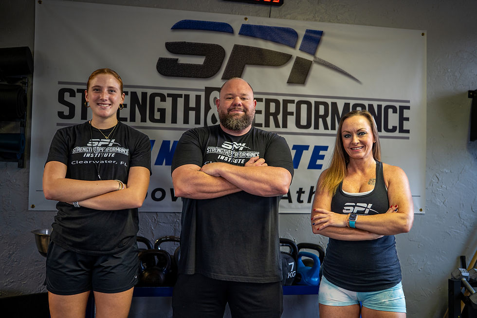 SPI strength coaches standing with their arms crossed posing in front of the SPI banner