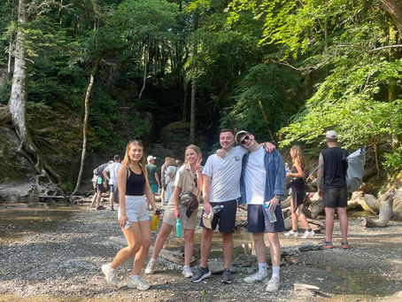Friends visiting a hidden woodland waterfall near Top of the Woods glamping site in Pembrokeshire, Wales, enjoying a group nature break