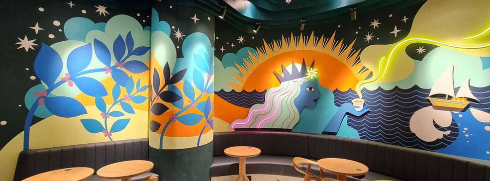 Colorful maritime-themed mural in Starbucks Blue Waters Dubai featuring ocean waves, sailing boats, and botanical designs with integrated neon lighting and metal cutouts