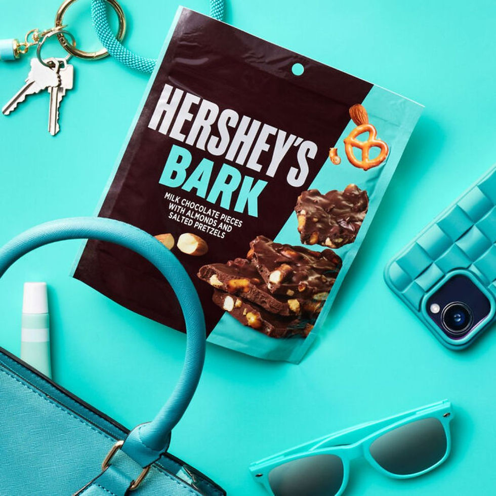 Lifestyle photo of HERSHEY'S Bark chocolate bag on teal background with accessories
