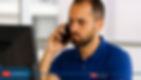 Homem de camisa azul fala ao celular diante do computador, em escritório claro, com ar preocupado; logo ICMP Consultoria em TI.