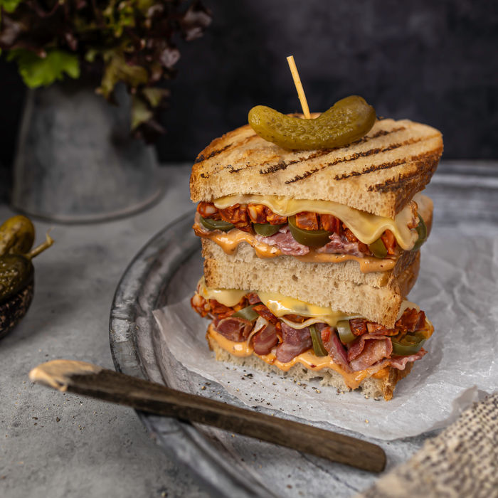 Grilled sandwich with layers of meat, cheese, and a pickle.