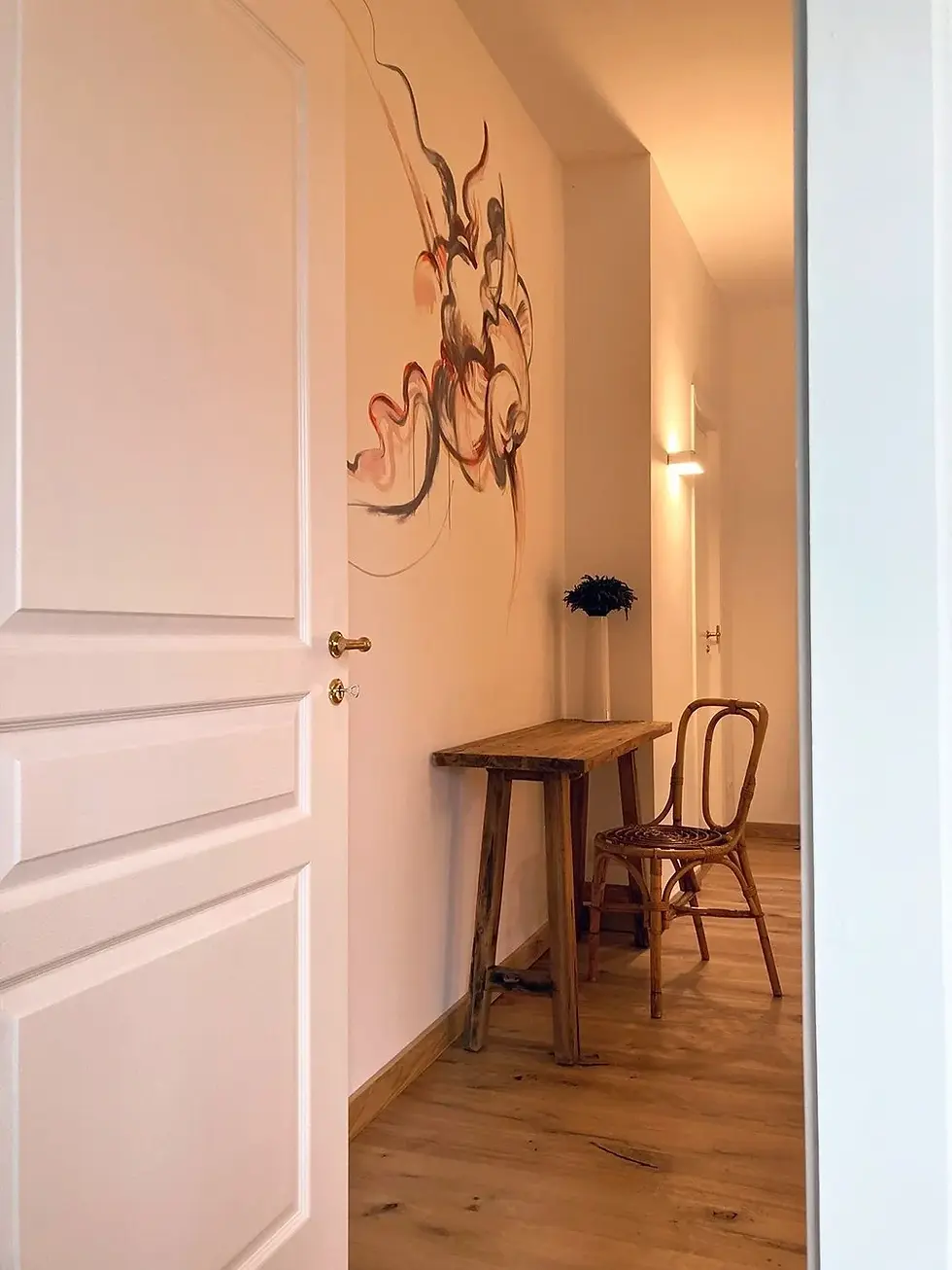 White door and hallway interior with desk and decorative wall art.