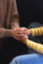 vertical-midsection-biracial-lesbian-couple-holding-hands-sitting-couch-home.jpg