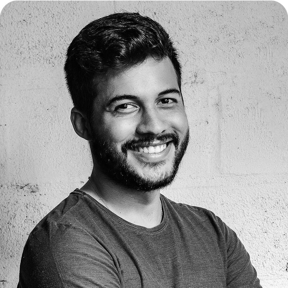 Smiling man with a beard and a casual shirt against a white wall
