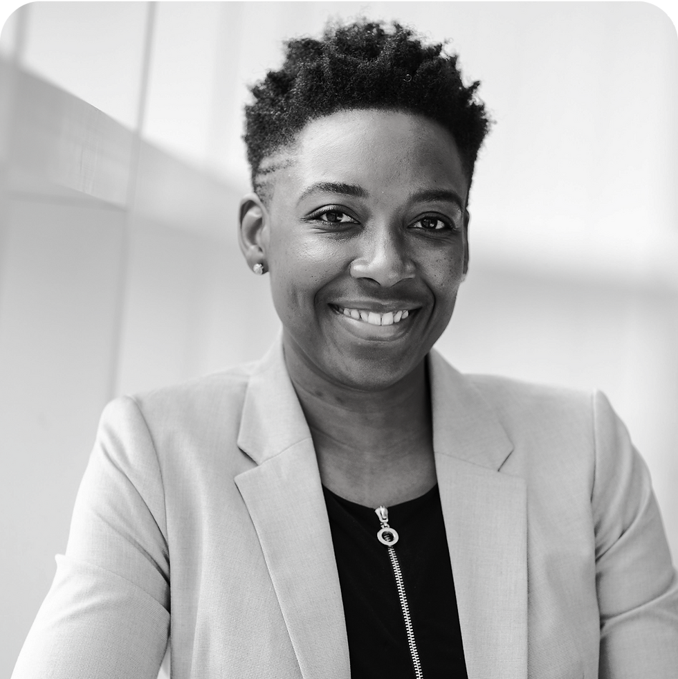 Smiling woman poses, wearing a blazer and looking directly at the camera with joy.