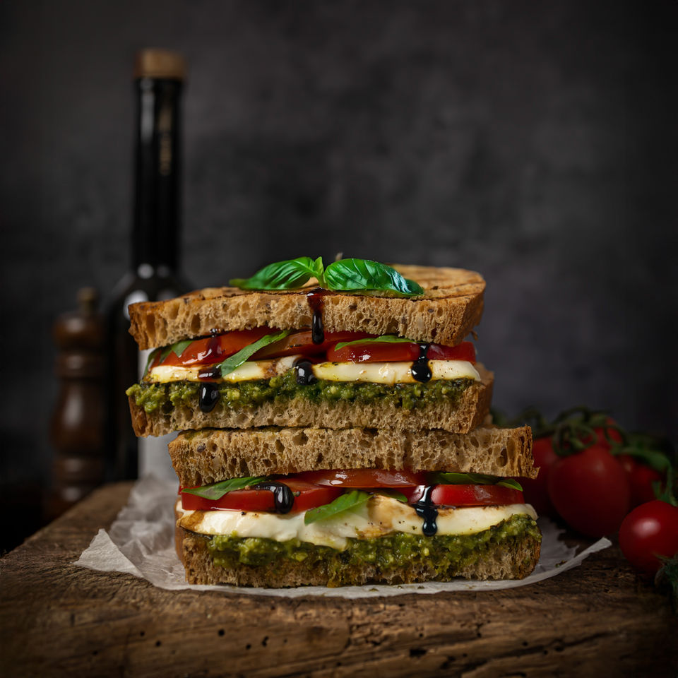 Stacked sandwich with pesto, mozzarella, tomato, basil