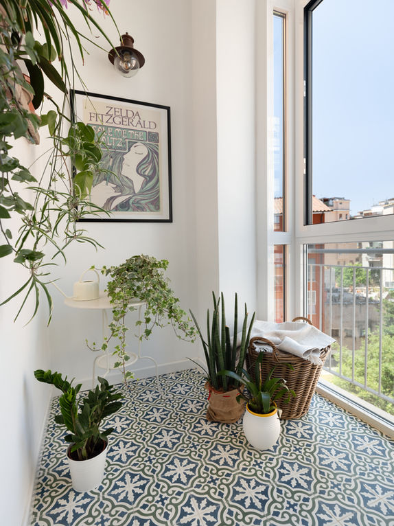 Vista della veranda con pavimento in cementine decorate artigianali colori dominanti blu verde e bianco infisso bianco che chiude la veranda e pareti bianche.