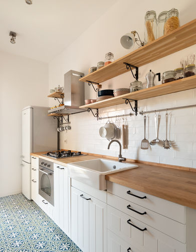 Vista della cucina in linea tutta su una parete, a terra cementine decorate artigianali. Mensole in legno sopra la cucina fatte su misura.