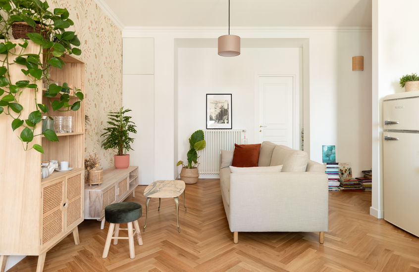 foto del living dell'appartamento con vista su angolo divano tavolo da caffe e mobili contenitivi sulla sinistra con dietro carta da parati con motivo vegetale all'inglese