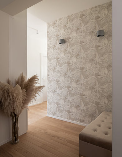 particolare di ingresso con carta da parati con motivo floreale e applique, parquet posato in listoni in rovere e panca imbottita