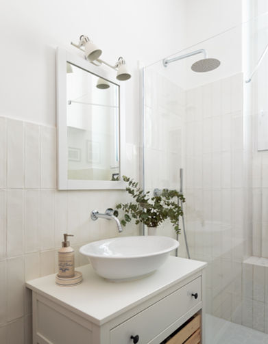 Foto del bagno. Colore dominante il bianco dell'intonaco, del lavabo e del mobile che lo sostiene. Si vede il vetro walk-in della doccia