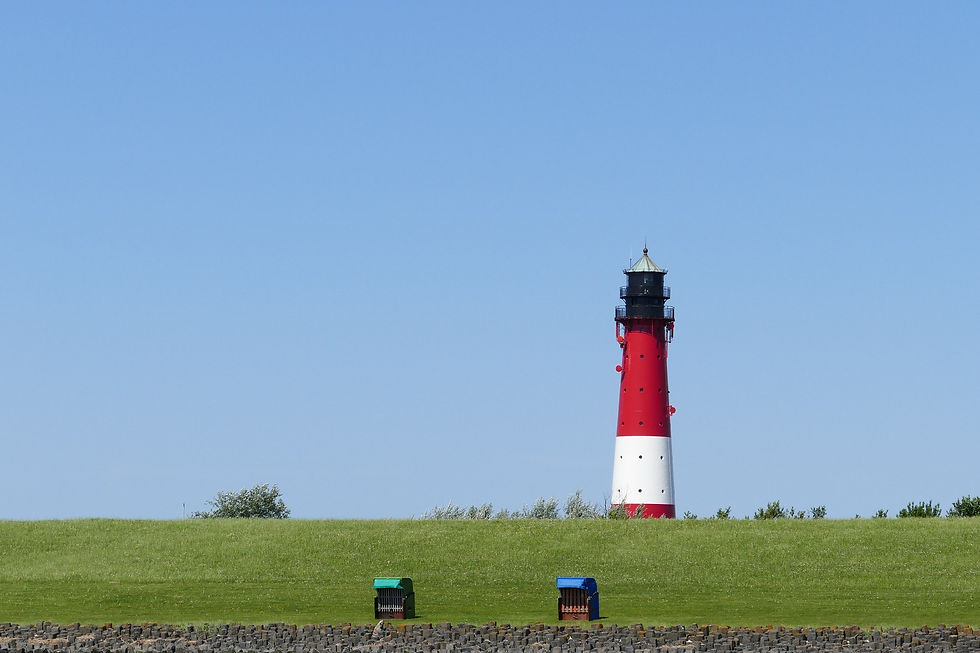 Grüner Deich der Insel Pellworm mit dahinterliegendem Leuchtturm