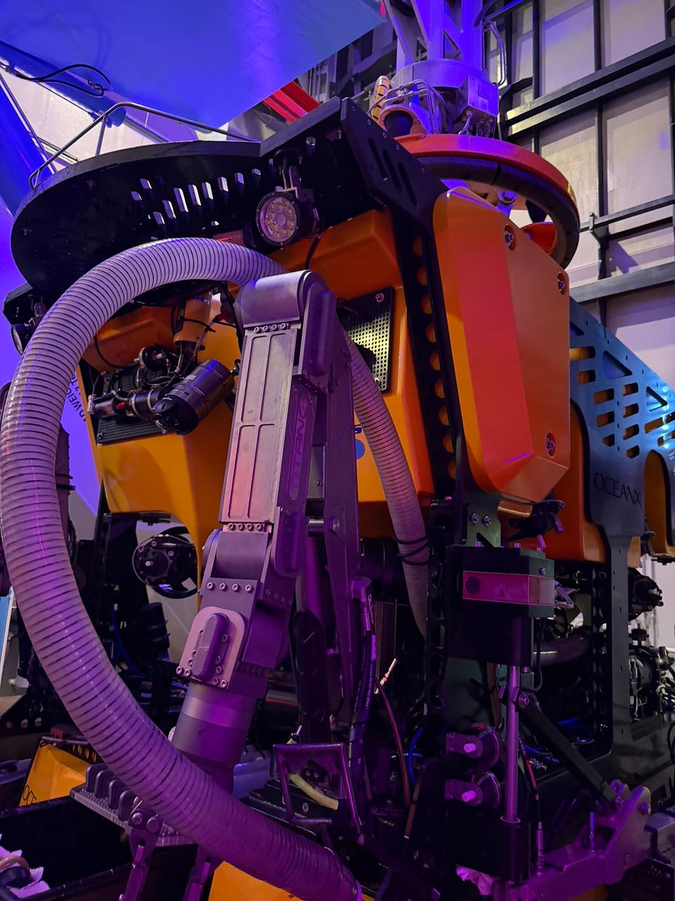 Close-up of a yellow underwater exploration vehicle showing mechanical arms, hoses, and technical equipment