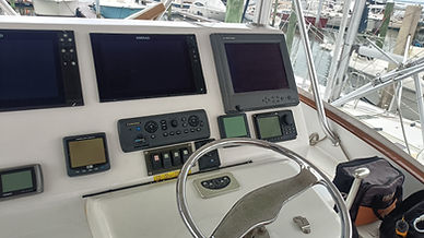 boat console with different brand electronics and different versions of, vhf radio, boat sonar, boat radar, fish finder, and switches on a center console boat, fishing boat