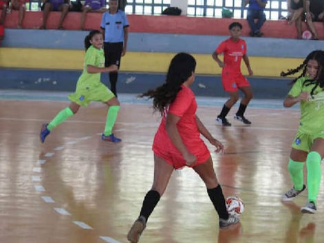 Jovens atletas deodorenses jogam com bons uniformes, bola nos pés, em uma quadra estruturada.