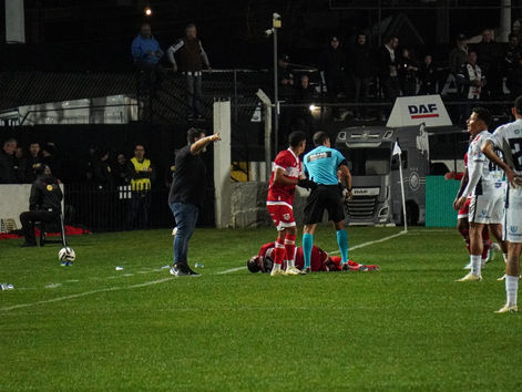 Clima tenso no Germano Krüger: jogador do CRB recebe atendimento após entrada dura, enquanto arbitragem e jogadores cercam o lance que paralisou a partida.