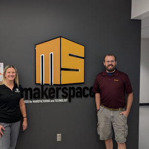 Picture of Dr.Karen and Nick Devine behind MakerSpace logo