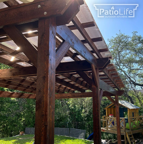 Custom tiered pergola in stained western red cedar with a bronze polycarbonate roof in Austin, TX.