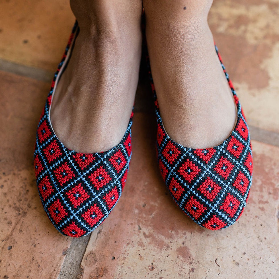 Woman wearing red flats with a blue diamond pattern and textured flooring.