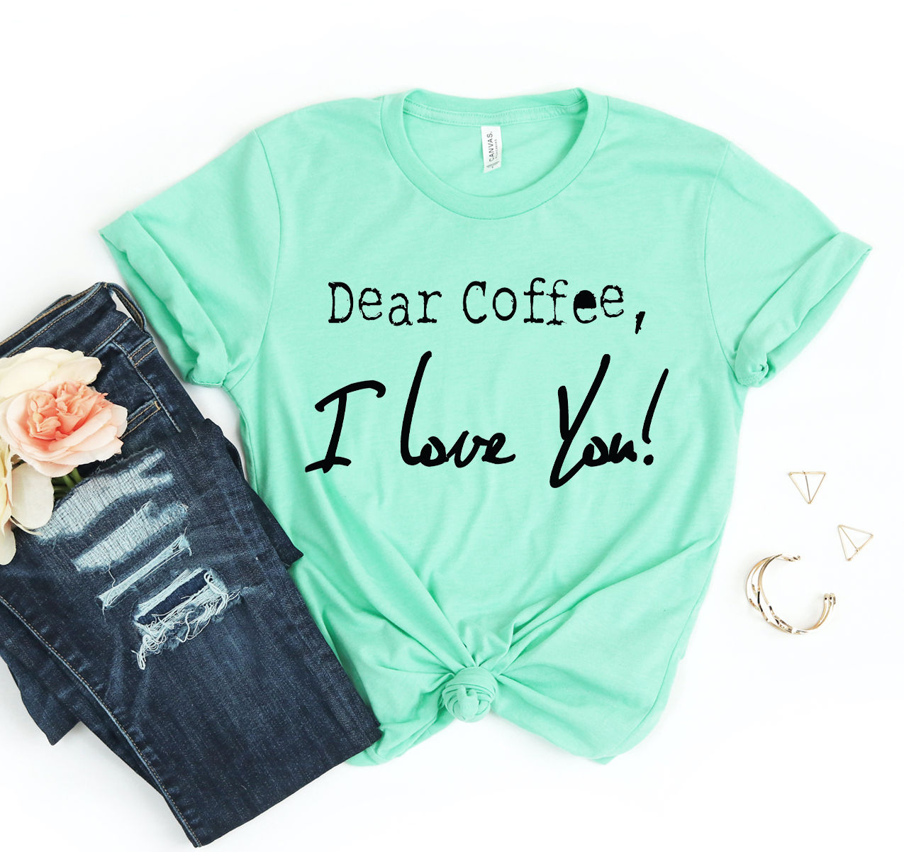 Green T-shirt says Dear Coffee, I Love You! laid on jeans.