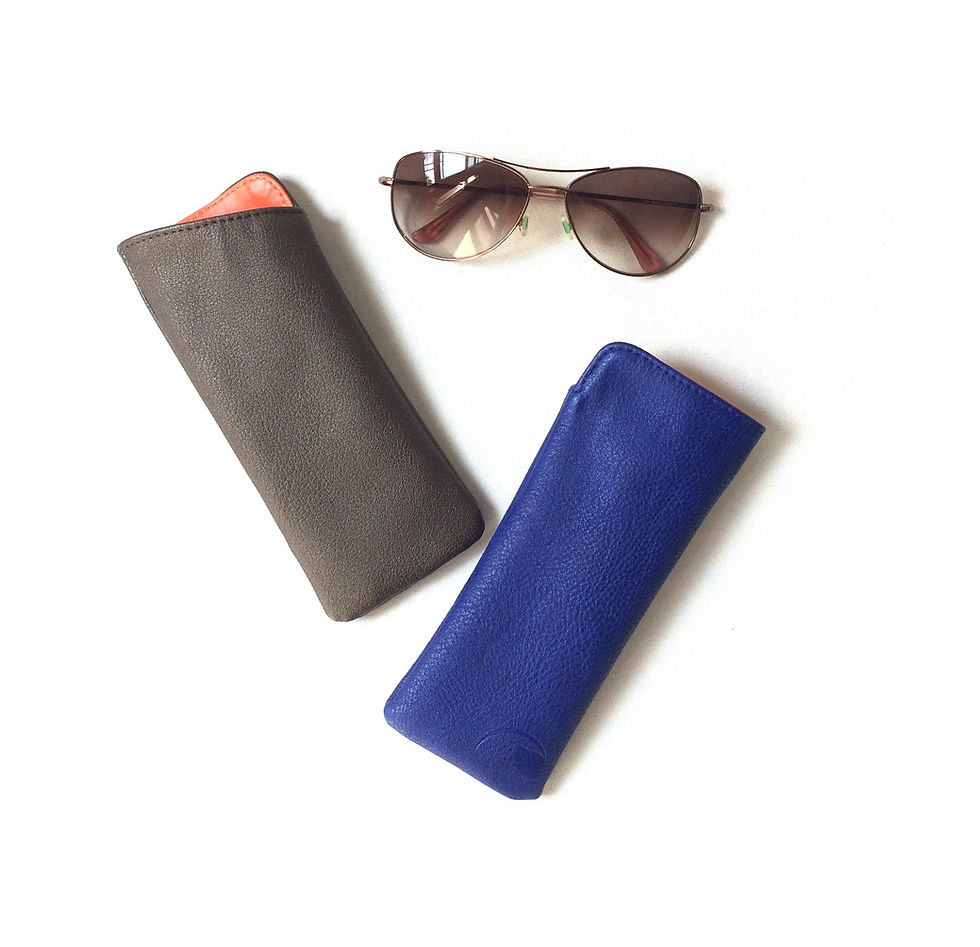 Sunglasses resting above two cases, Lucca - Luxury Wallet, on a white background.