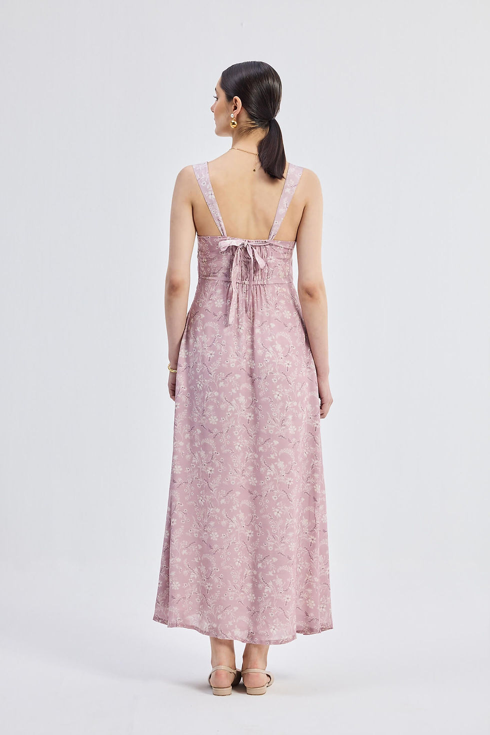 Woman wearing floral dress, back view, with bow detail, standing. Khaam Fefalene