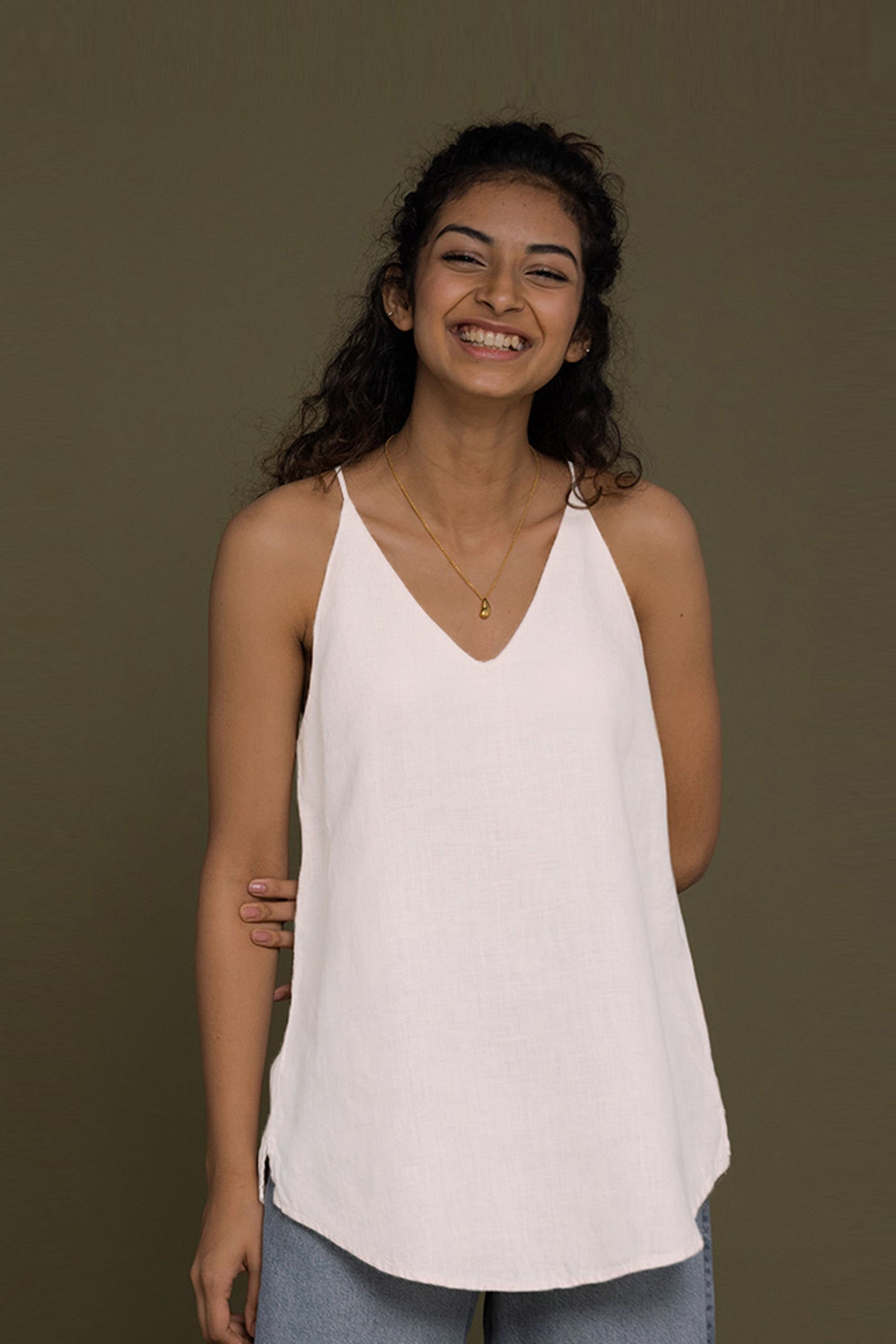 Smiling woman wearing white top posing against a green background.