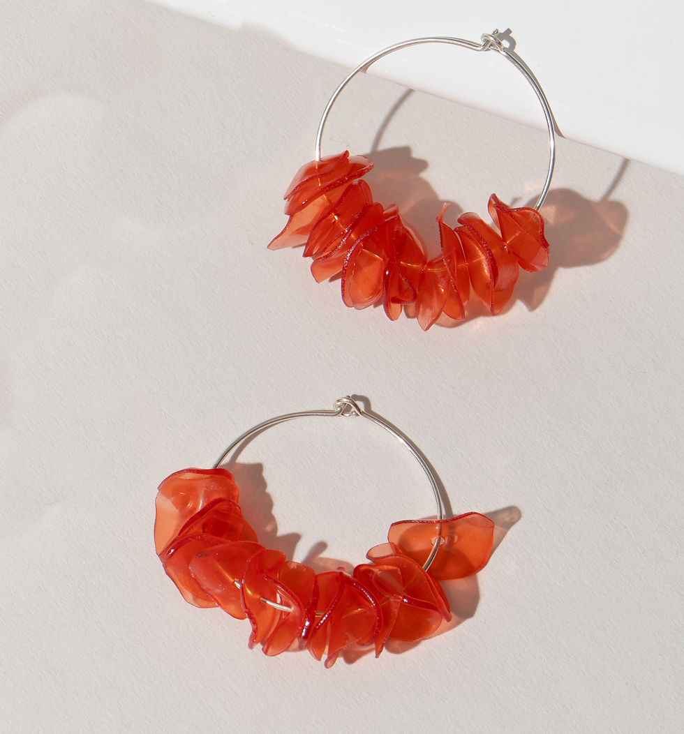Two red hoop earrings on white background with shadows, Khaam Fefalene.
