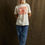 Thumbnail: Woman wearing Tacos and Beer shirt with jeans, standing, brown background.