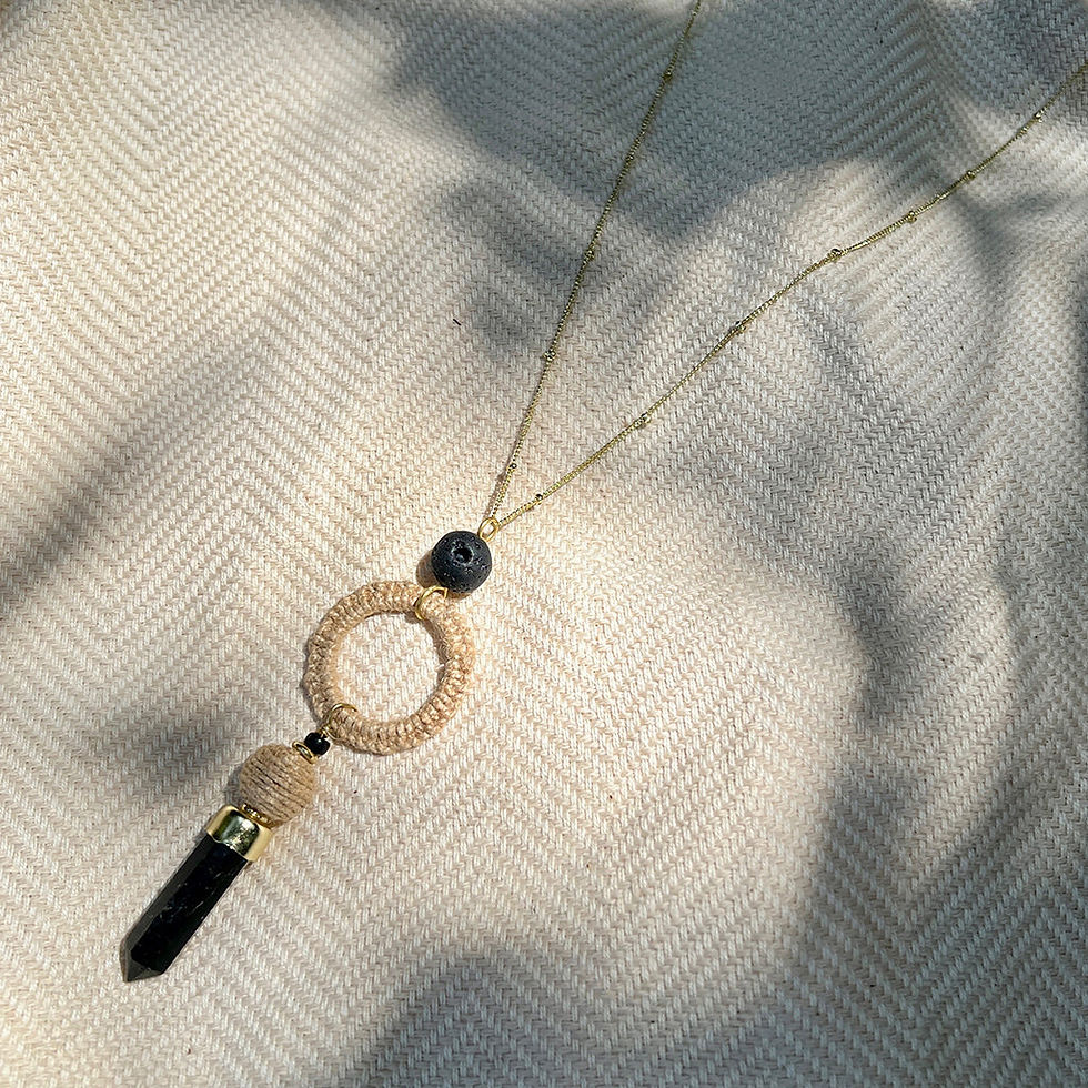 Elegant necklace with a circular pendant and black crystal, neutral background.