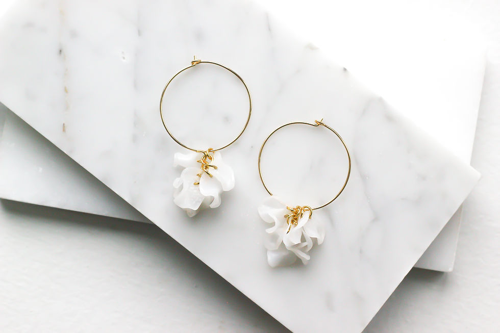 Elegant gold hoop earrings with white floral petals, fashionable jewelry design.