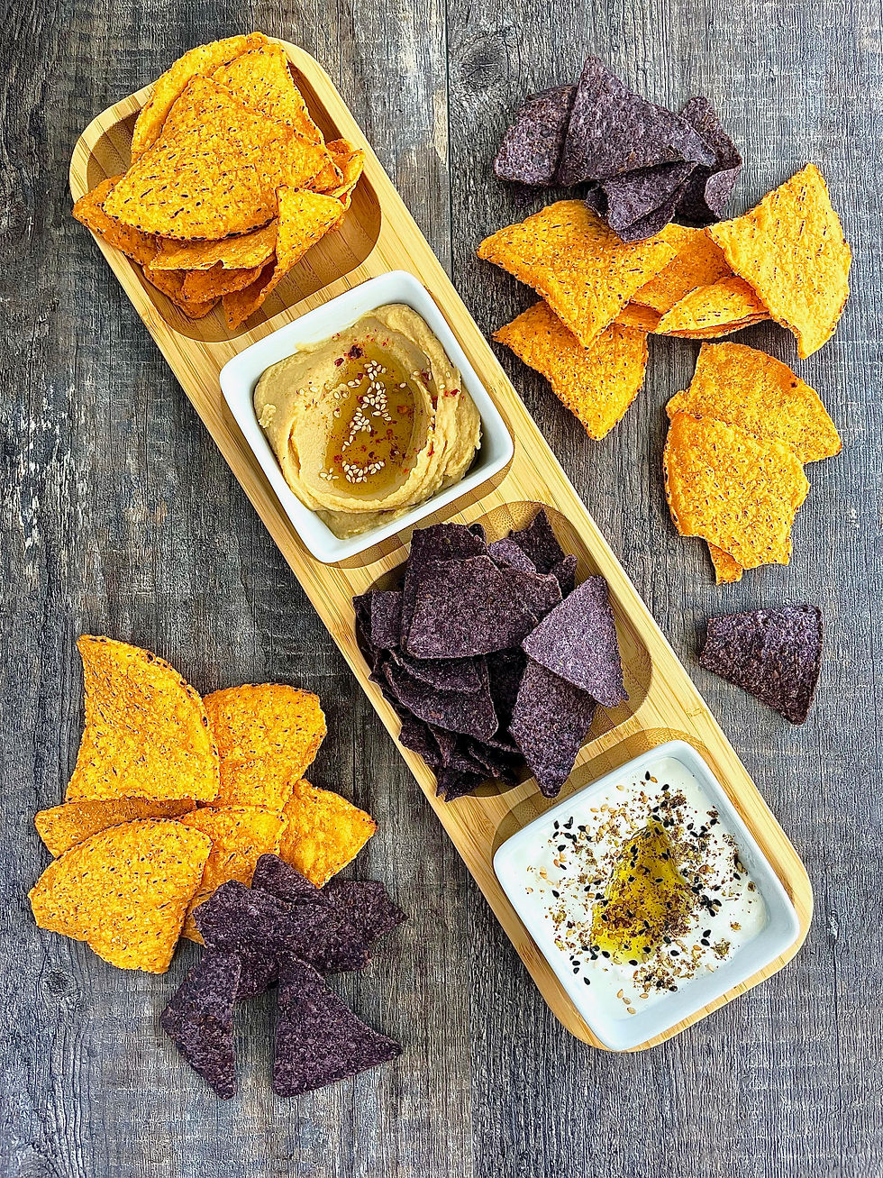 Wooden serving tray with chips, hummus, and dip for appetizer snack