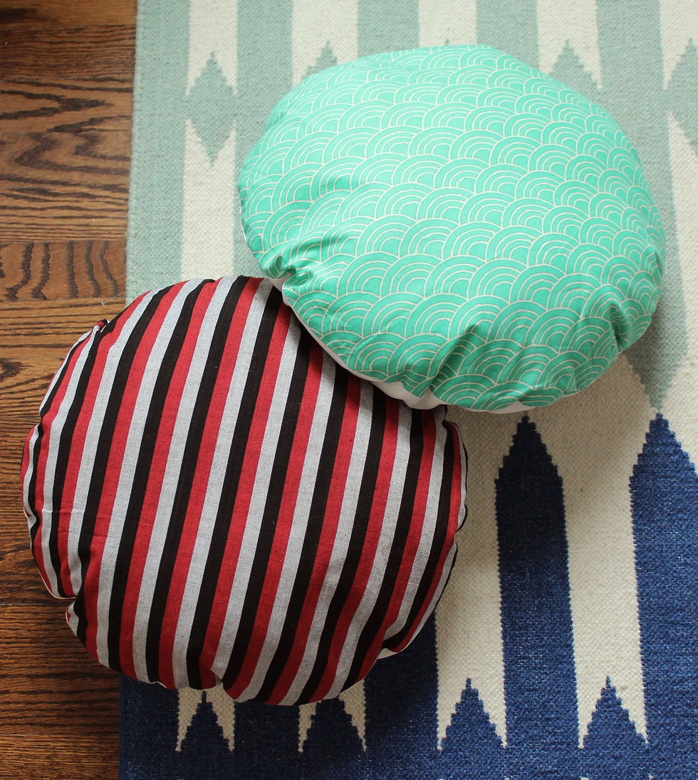 Two round pillows with stripes and dots over a blue pattern carpet