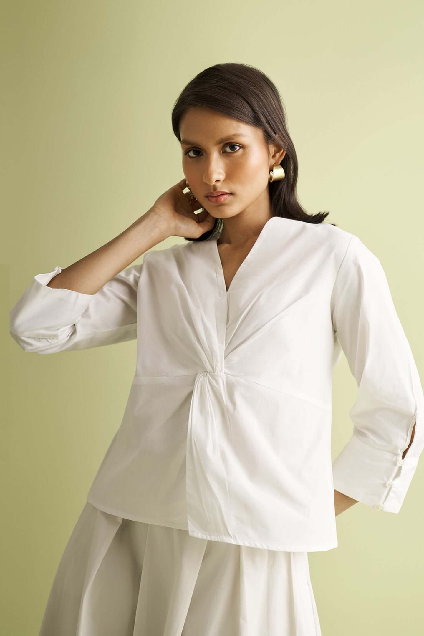 Woman wearing white shirt with knot detail, looking at camera's view