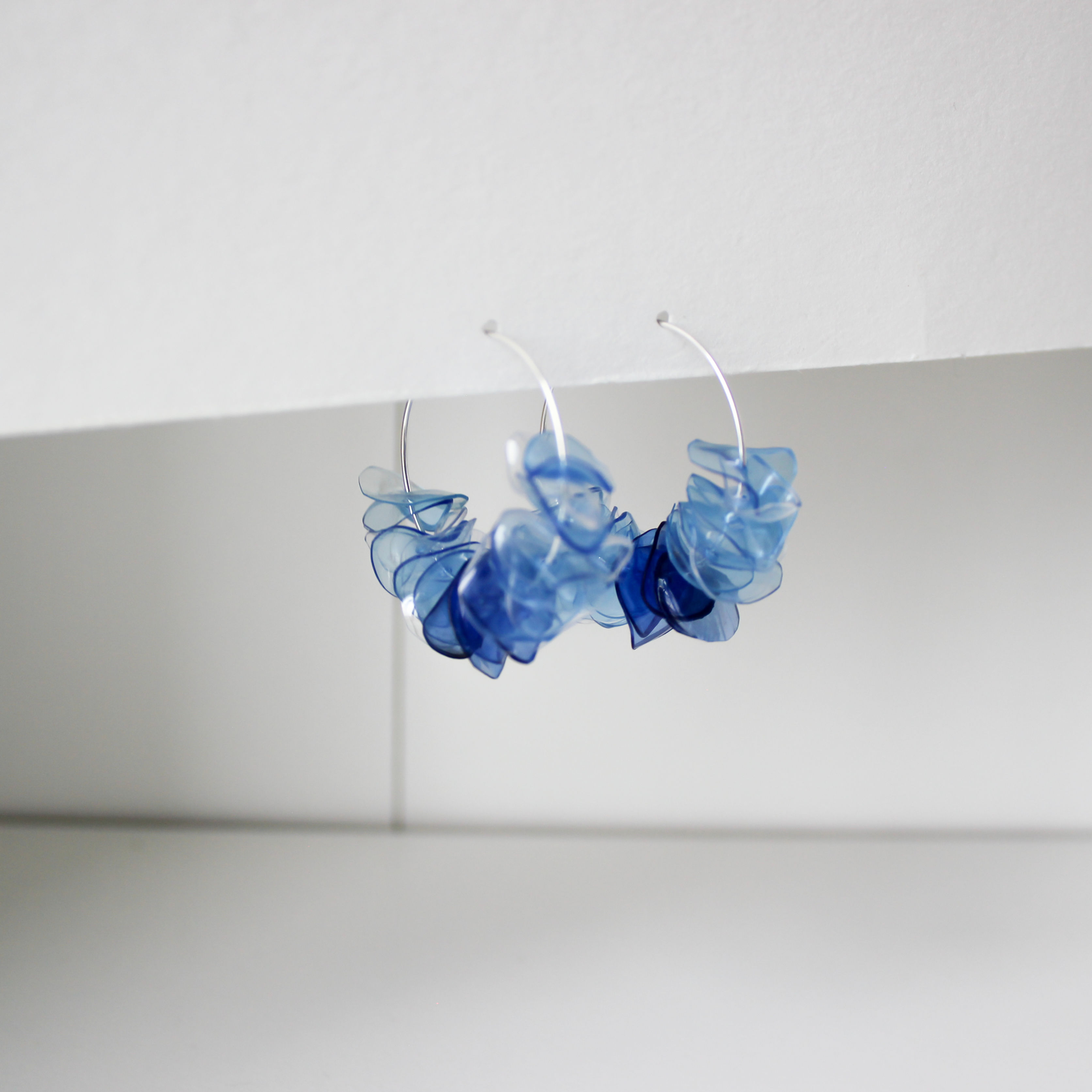 Blue hoop earrings, dangling, with white background, stylish, and contemporary design.