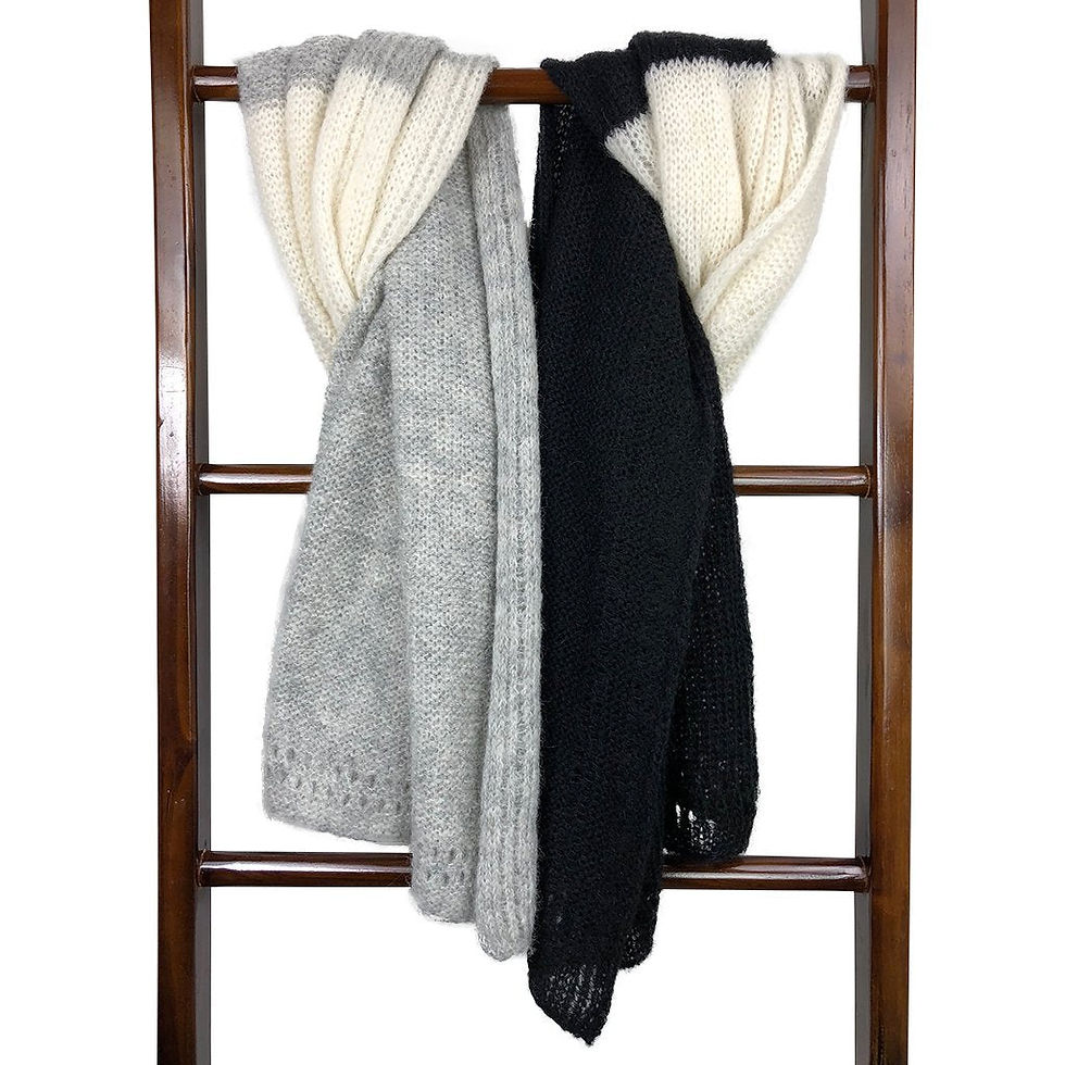 Three knitted scarves hanging on a wooden ladder against a white background.