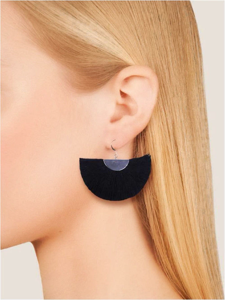 Woman wearing black semi-circle earrings with a clear disc detail, close-up shot.