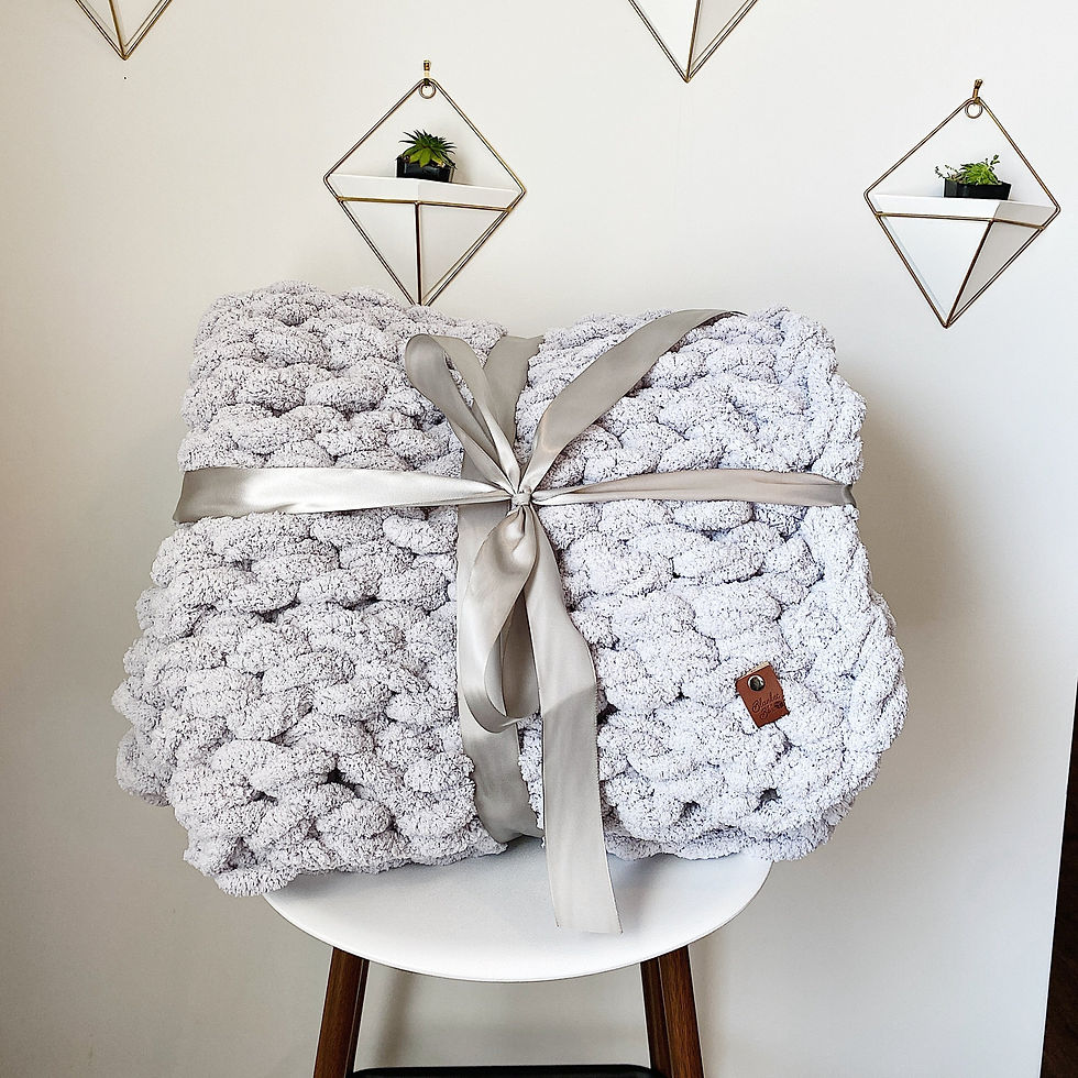 Cozy knitted blanket wrapped with ribbon, sitting on a white stool, home decor.