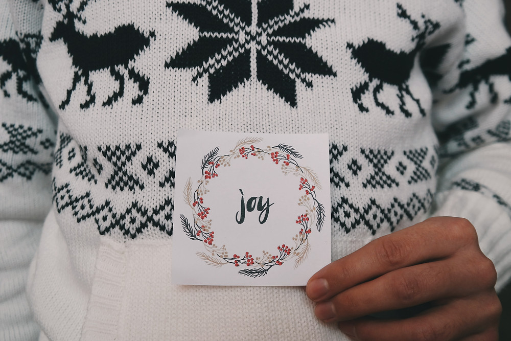 Person holding a card with the word "Joy" written on it
