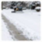 Residential snow removal with a plow clearing a street.