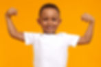 a young boy smiles and flexes his muscles proudly to show how children's dental health keeps you strong and healthy