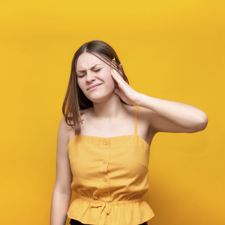 woman holding her ear in pain from tinnitus